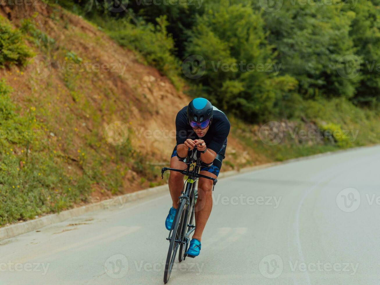 Full length portrait of an active triathlete in sportswear and with a protective helmet riding a bicycle. Selective focus photo