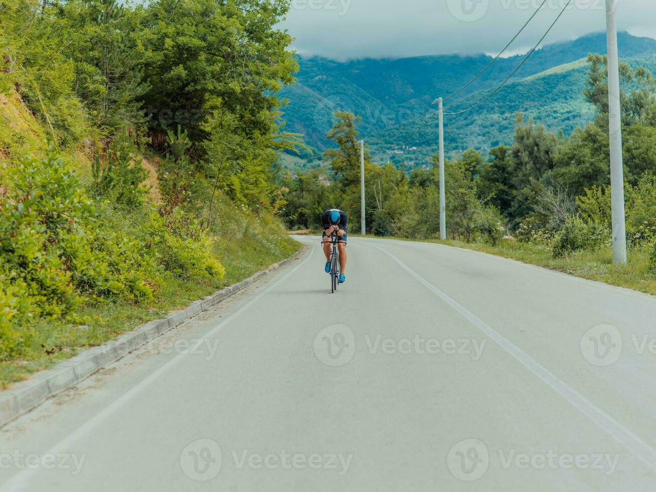 Full length portrait of an active triathlete in sportswear and with a protective helmet riding a bicycle. Selective focus photo