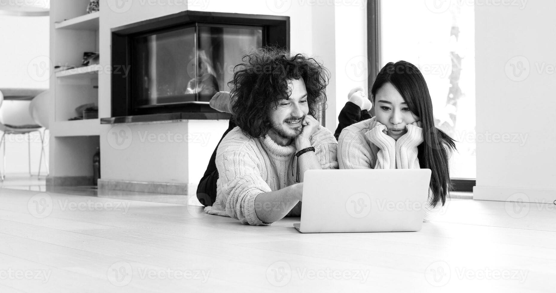 young multiethnic couple using a laptop on the floor photo