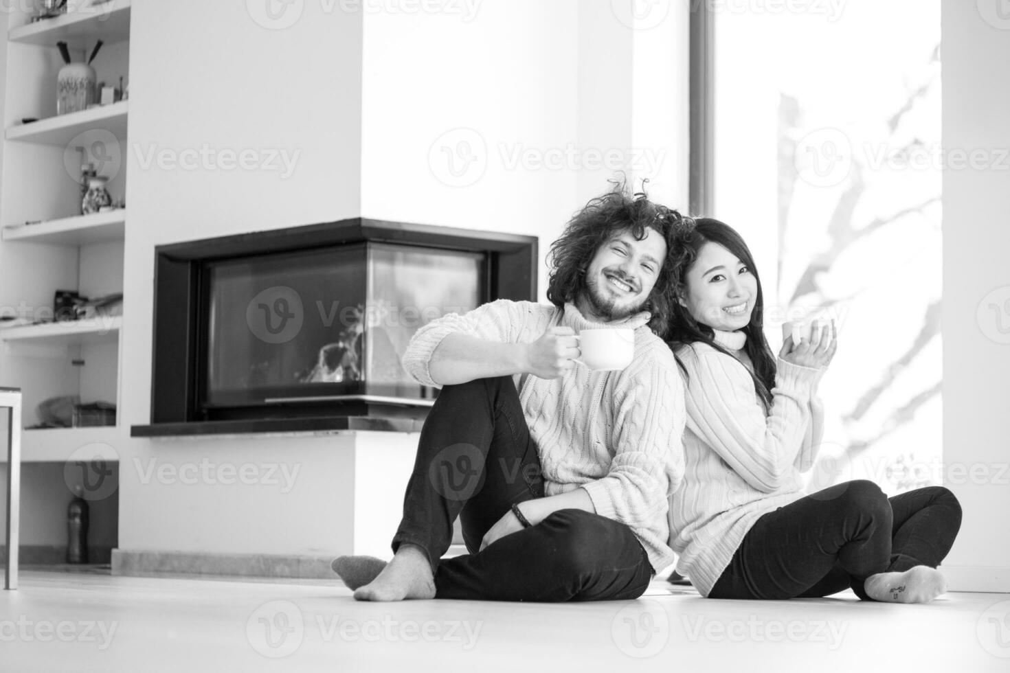 feliz pareja multiétnica frente a la chimenea foto