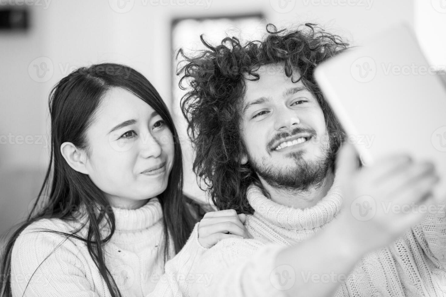 multiethnic couple using tablet computer in front of fireplace photo
