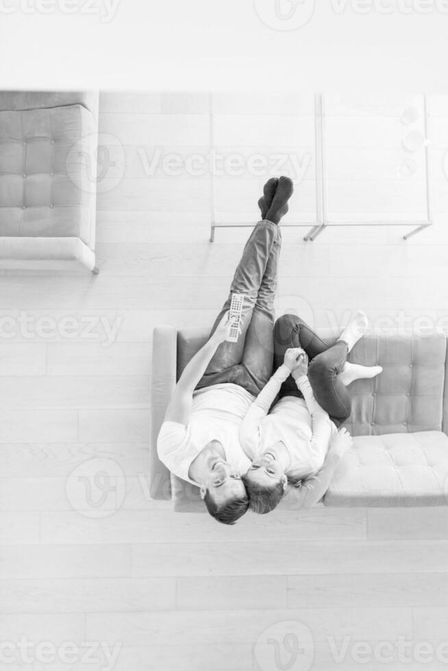 Young couple on the sofa watching television top view photo