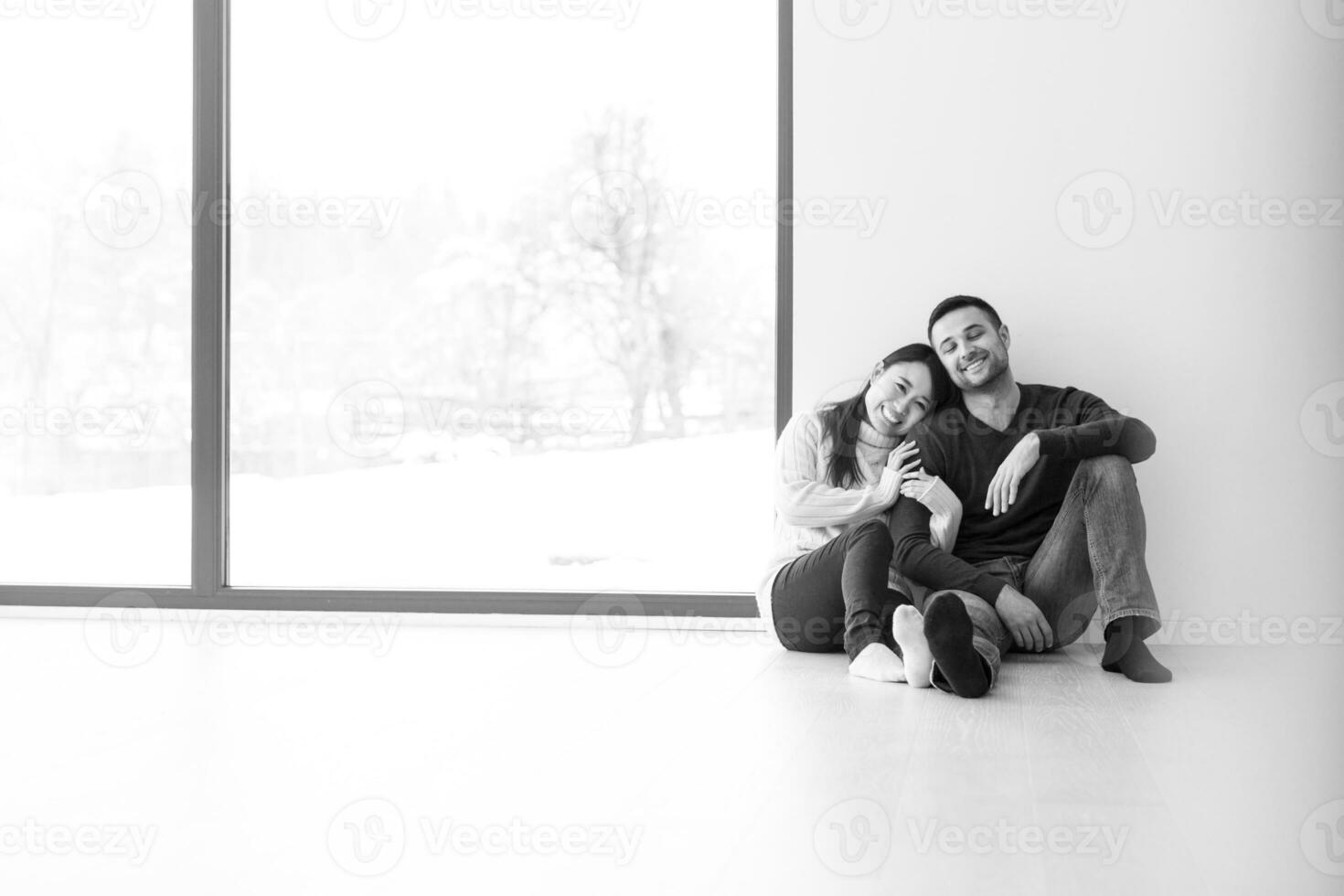 pareja multiétnica sentada en el suelo cerca de la ventana en casa foto
