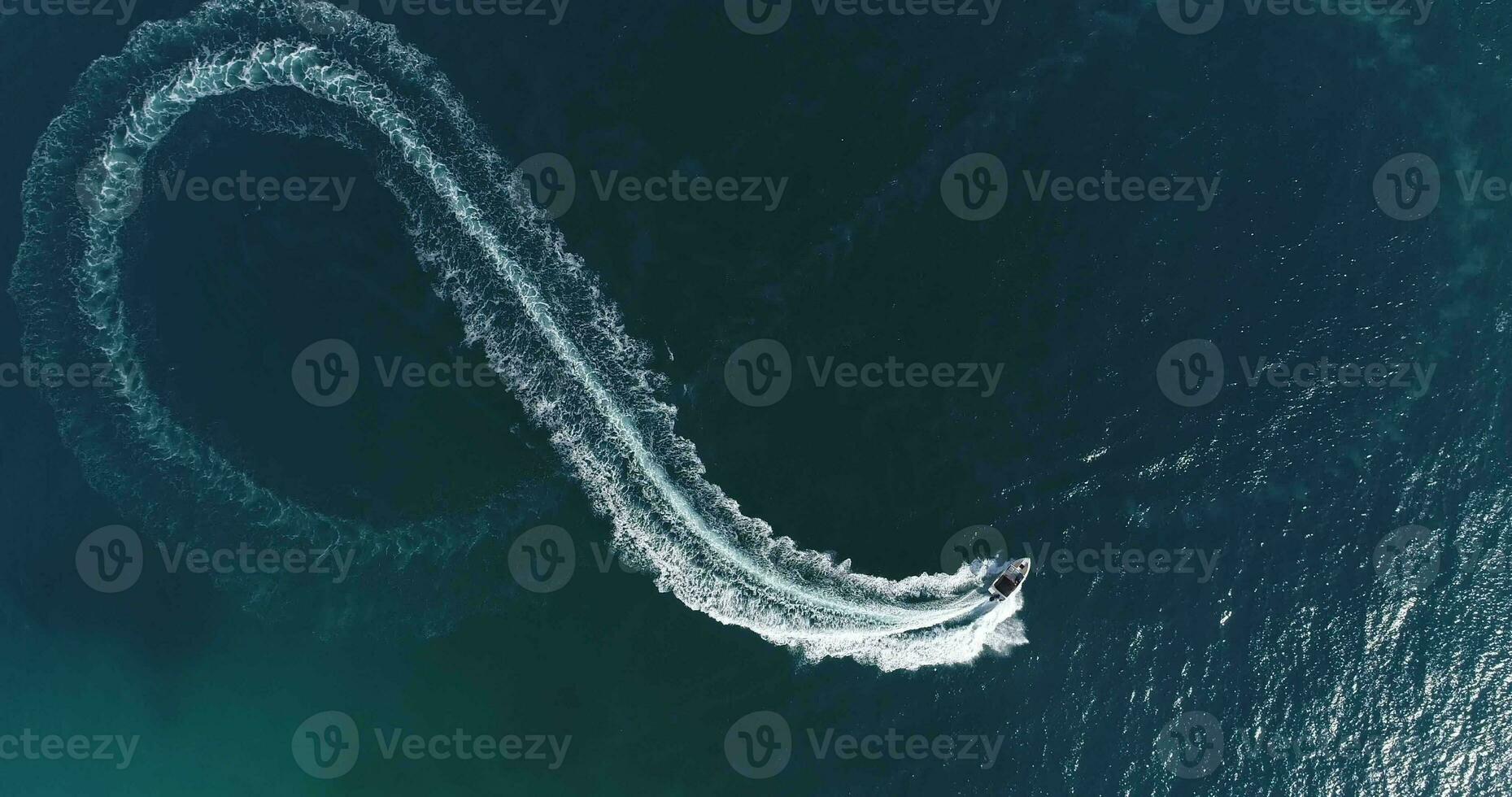 Aerial top view of a white pleasure boat on a summer day. Powerboat turn loop eight on the sea making infinity future concept. photo