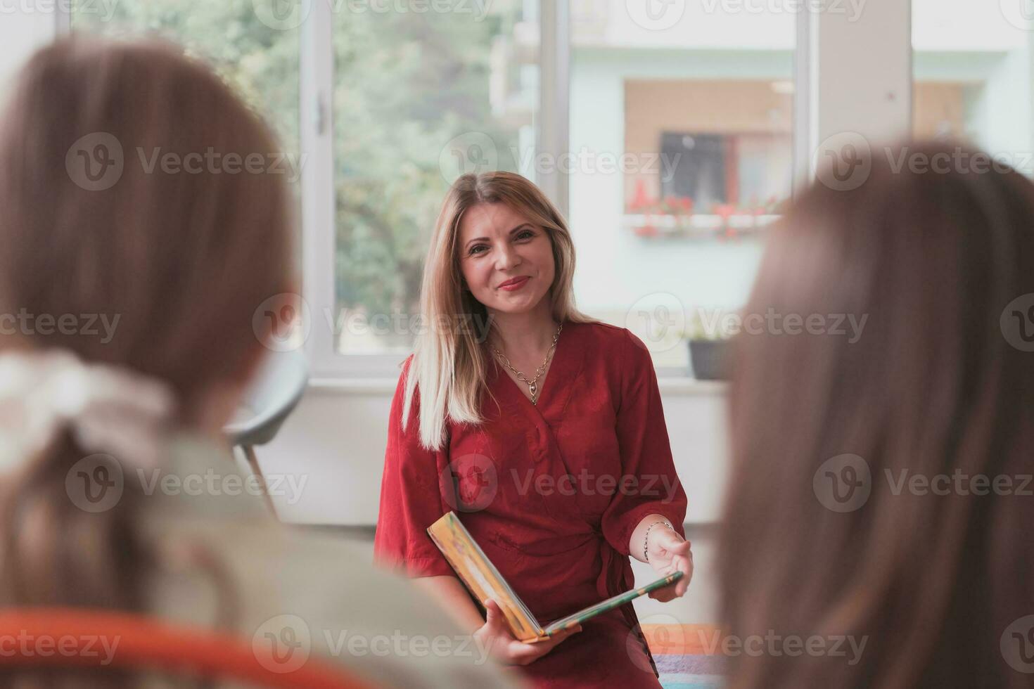 Reading time in an elementary school or kindergarten, a teacher reads a book to children in an elementary school or kindergarten. The concept of pre-school education. Selective focus photo
