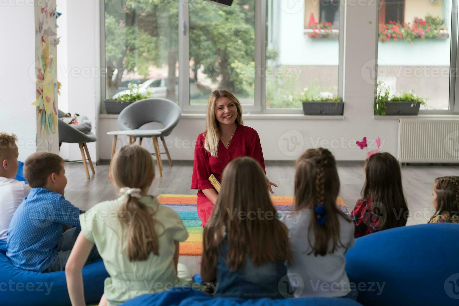 Reading time in an elementary school or kindergarten, a teacher reads a book to children in an elementary school or kindergarten. The concept of pre-school education. Selective focus photo
