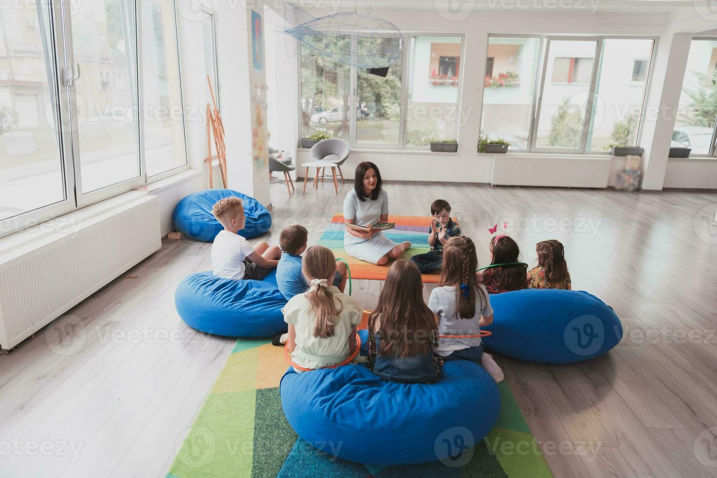 Reading time in an elementary school or kindergarten, a teacher reads a book to children in an elementary school or kindergarten. The concept of pre-school education. Selective focus photo