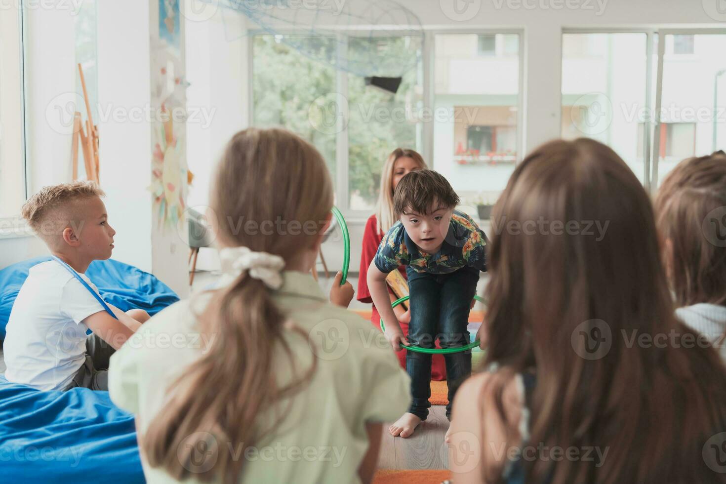 un contento hembra profesor sentado y jugando mano juegos con un grupo de pequeño Niños de escuela foto