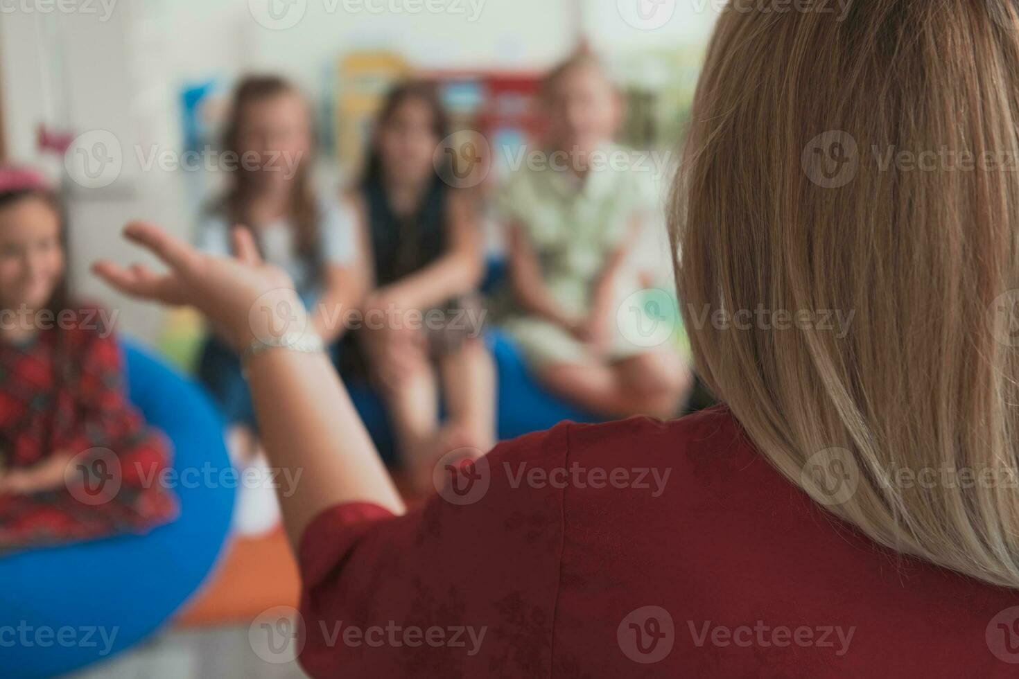 Reading time in an elementary school or kindergarten, a teacher reads a book to children in an elementary school or kindergarten. The concept of pre-school education. Selective focus photo
