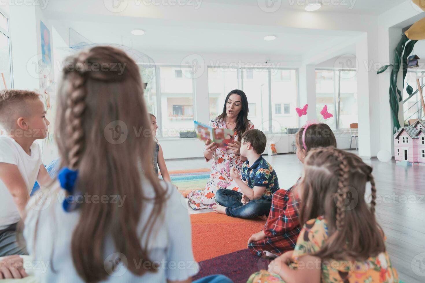 Reading time in an elementary school or kindergarten, a teacher reads a book to children in an elementary school or kindergarten. The concept of pre-school education. Selective focus photo