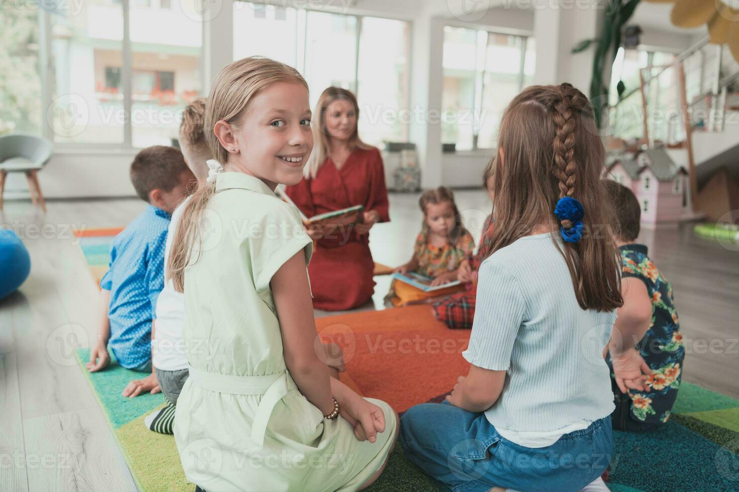 Reading time in an elementary school or kindergarten, a teacher reads a book to children in an elementary school or kindergarten. The concept of pre-school education. Selective focus photo