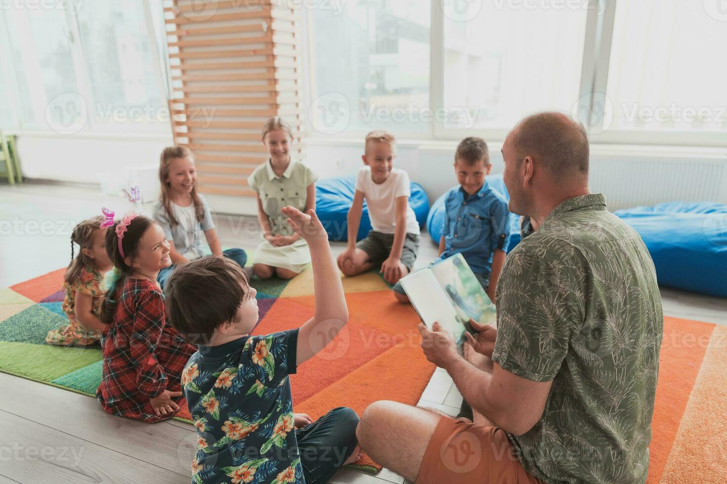 Reading time in elementary school or kindergarten, teacher reading a book to kids in elementary school or kindergaden. Selective focus photo