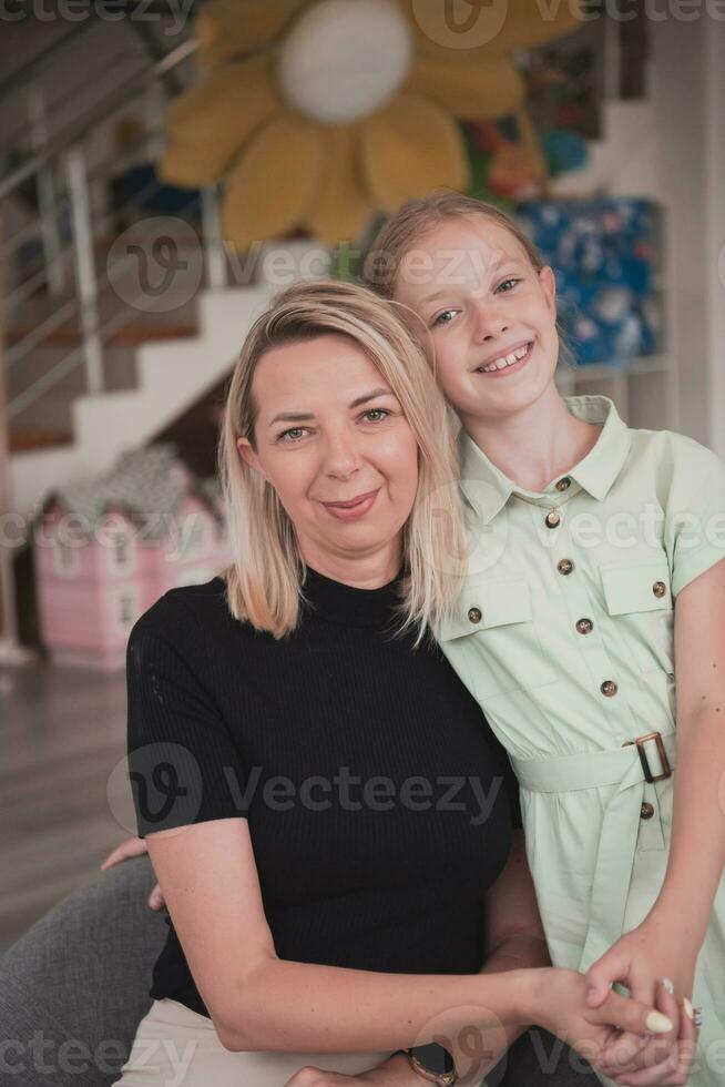 un linda pequeño niña Besos y abrazos su madre en preescolar foto