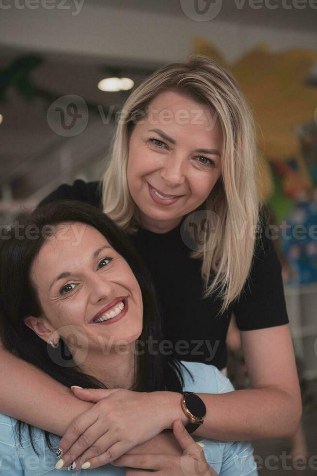 Portrait of two hugging female teachers in a preschool institution, in the background of the classrooms photo