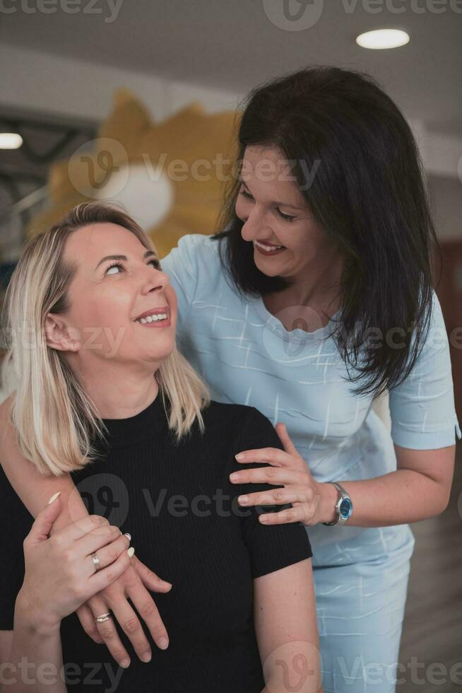 Portrait of two hugging female teachers in a preschool institution, in the background of the classrooms photo
