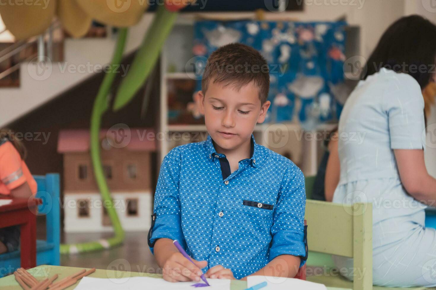 Cute girl and boy sit and draw together in preschool institution photo