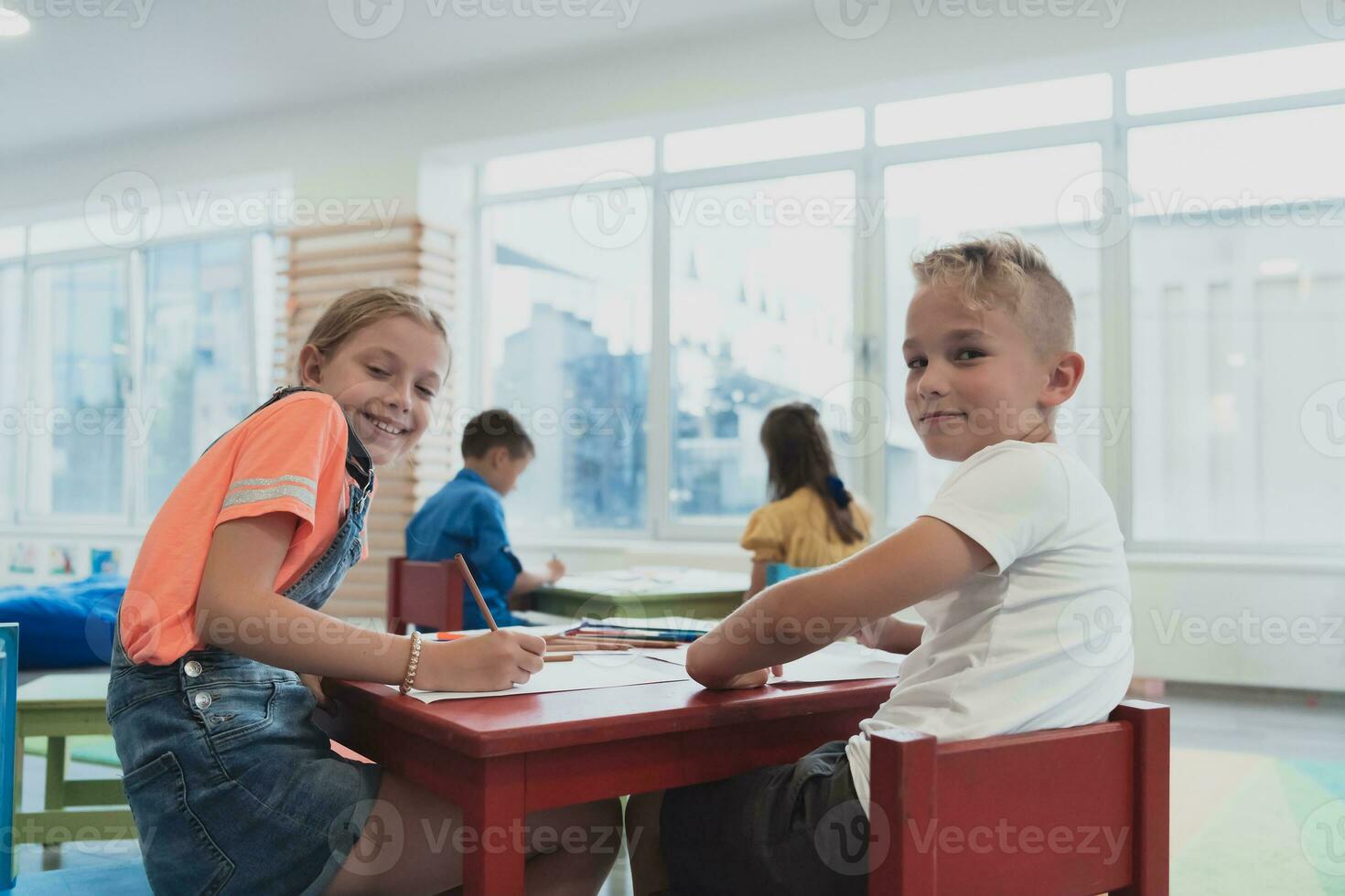 Cute girl and boy sit and draw together in preschool institution photo