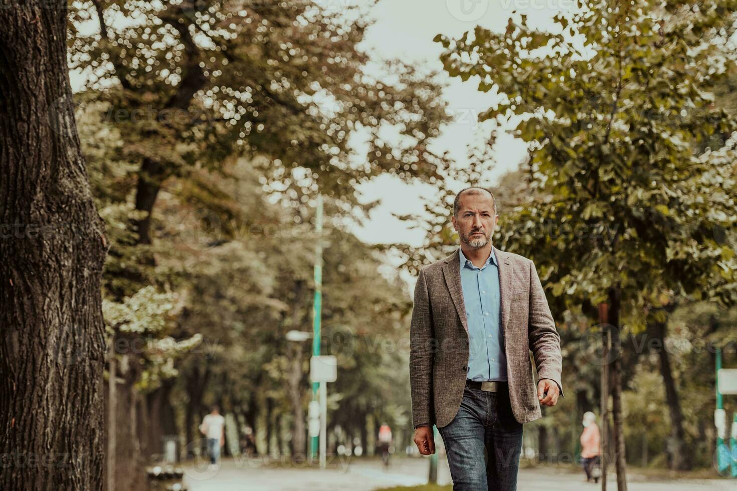 Focused businessman in a suit walking in the park photo