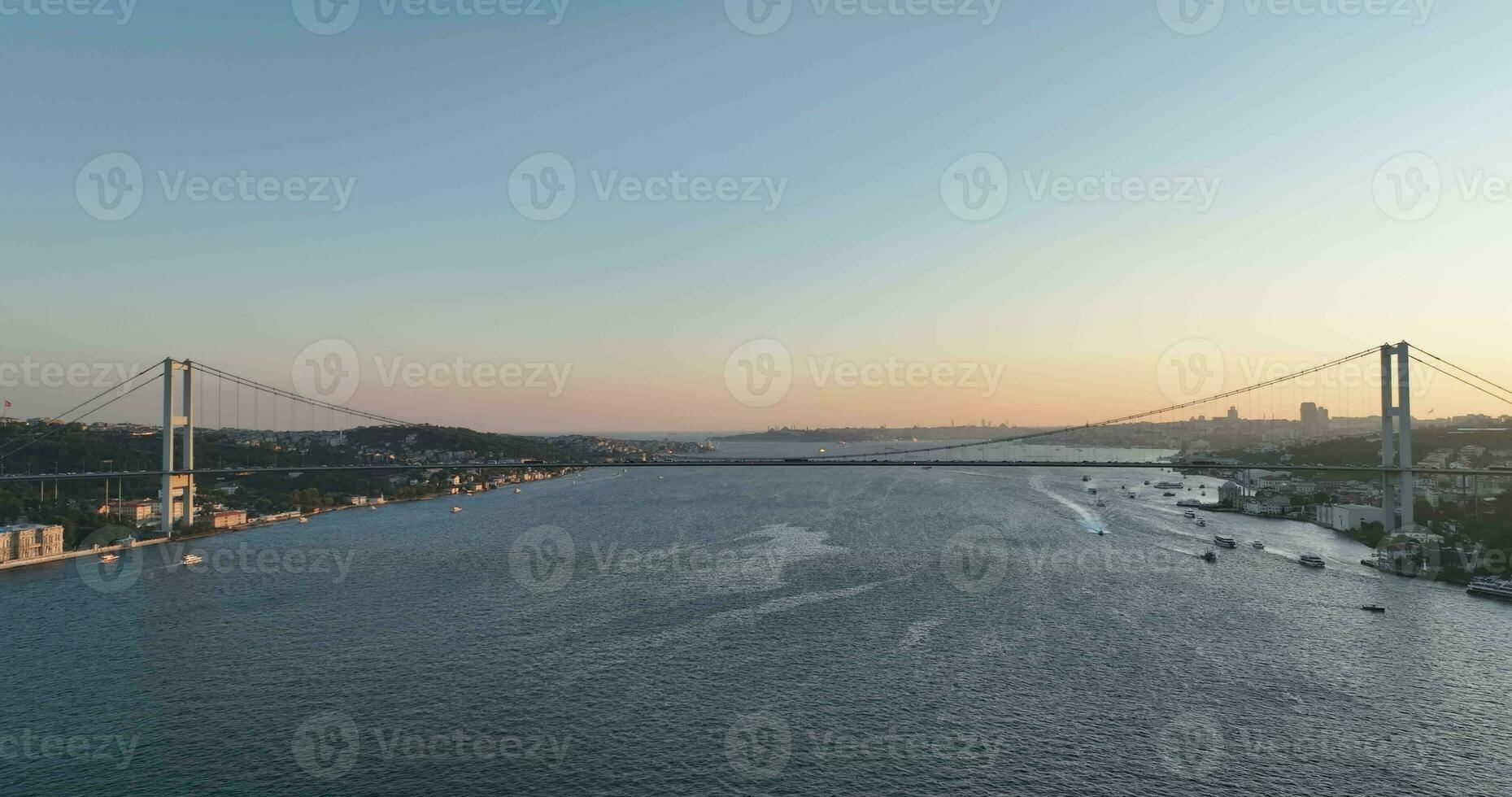 Istanbul Bosphorus Bridge and City Skyline in Background with Turkish Flag at Beautiful Sunset, Aerial slide orbiting and tracking shot photo
