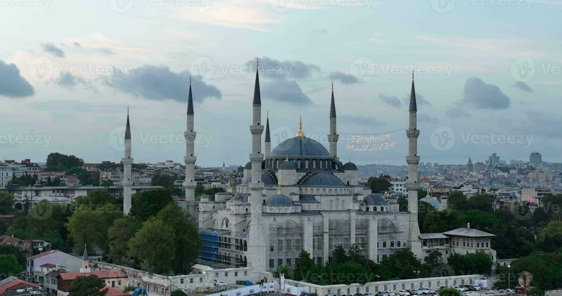 Establishing orbiting aerial drone shot of a Hagia Sophia Holy Grand Mosque with Bosphorus bridge and city skyline with a flag on the background in Fatih, Istanbul, Turkey at sunset. photo