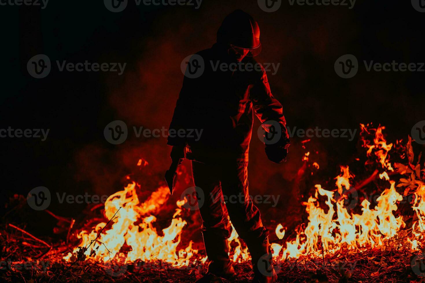 Firefighter at job. Firefighter in dangerous forest areas surrounded by strong fire. Concept of the work of the fire service photo