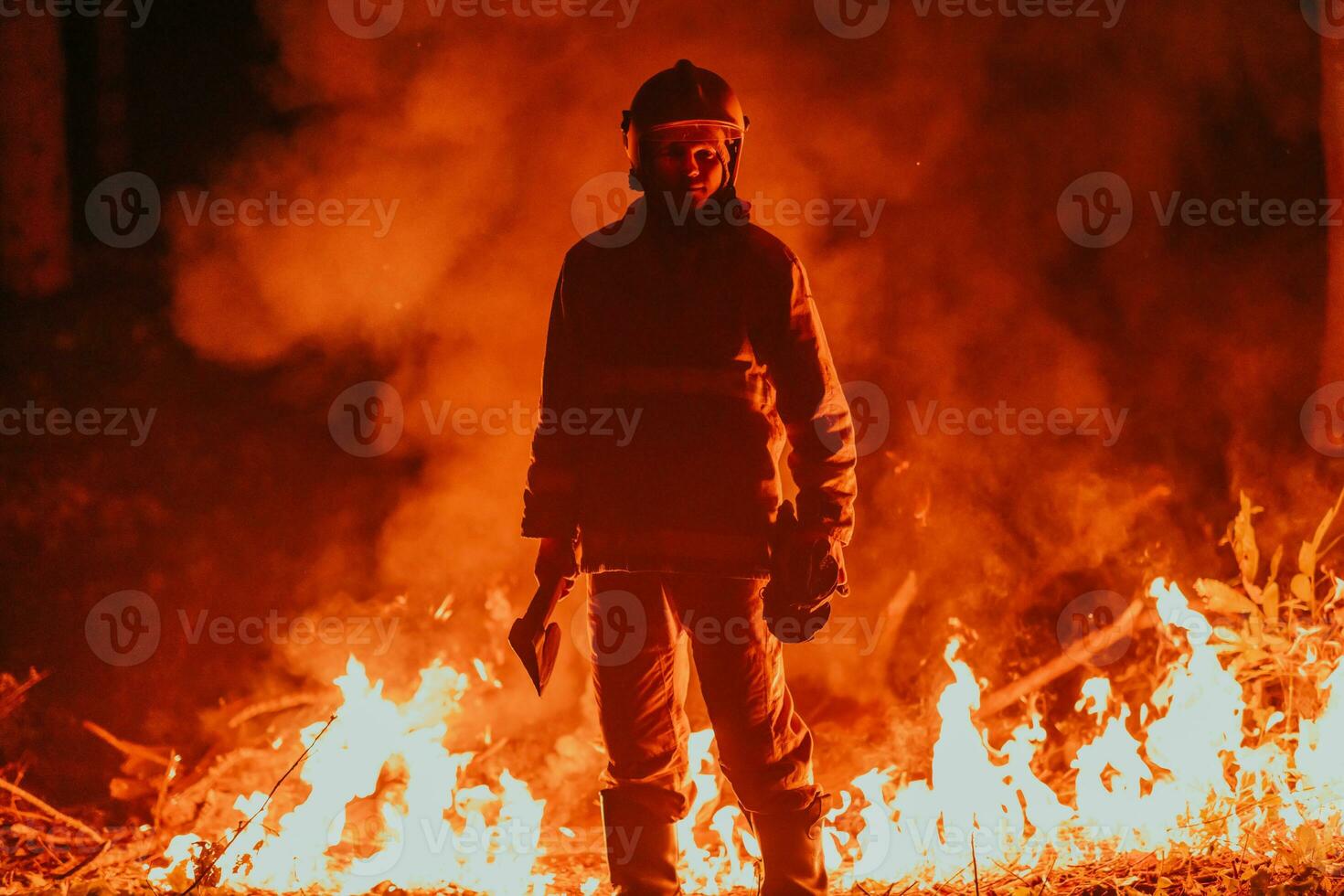 Firefighter at job. Firefighter in dangerous forest areas surrounded by strong fire. Concept of the work of the fire service photo