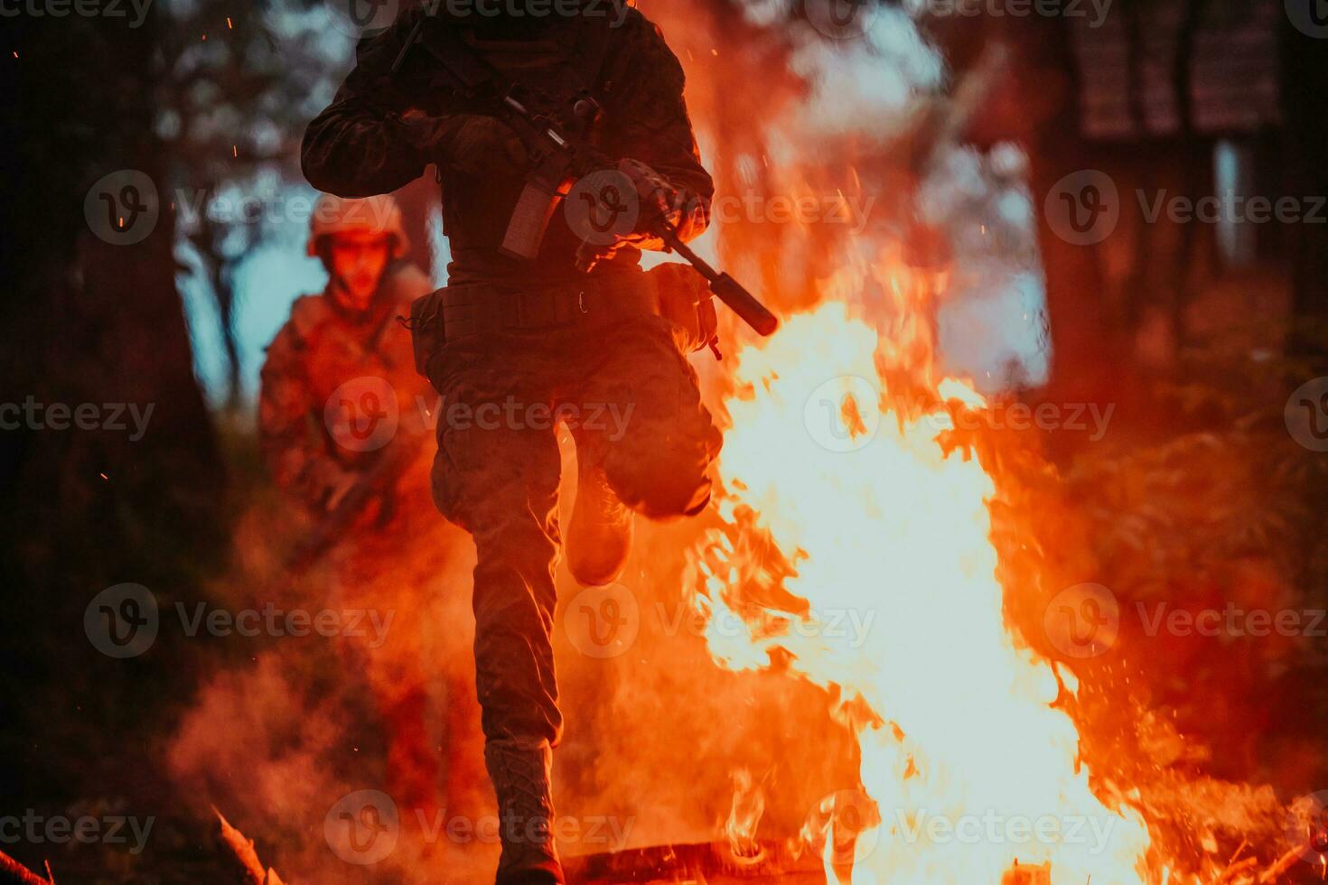 Soldier in Action at Night in the Forest Area. Night Time Military Mission jumping over fire photo
