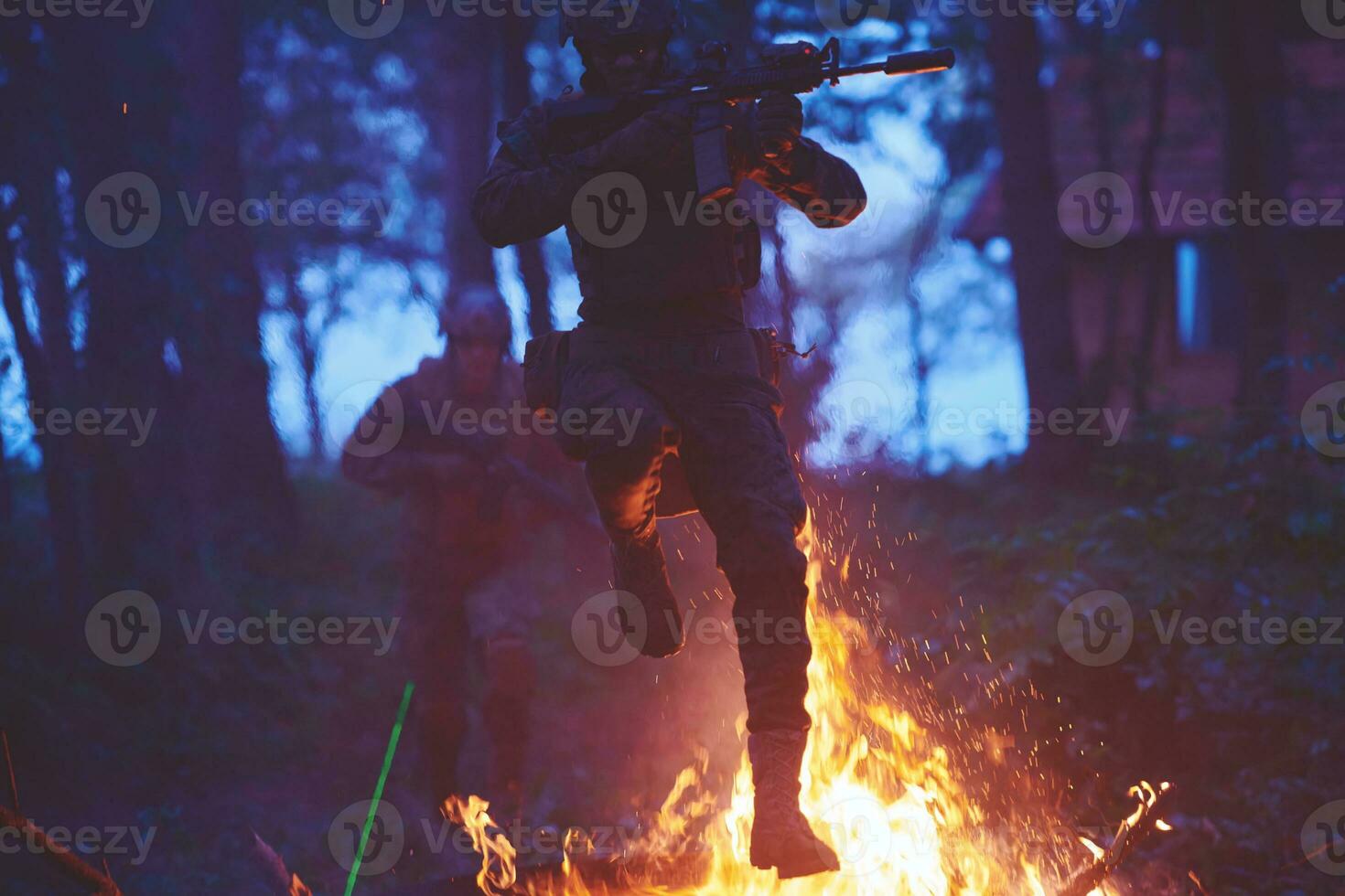 Soldier in Action at Night jumping over fire photo