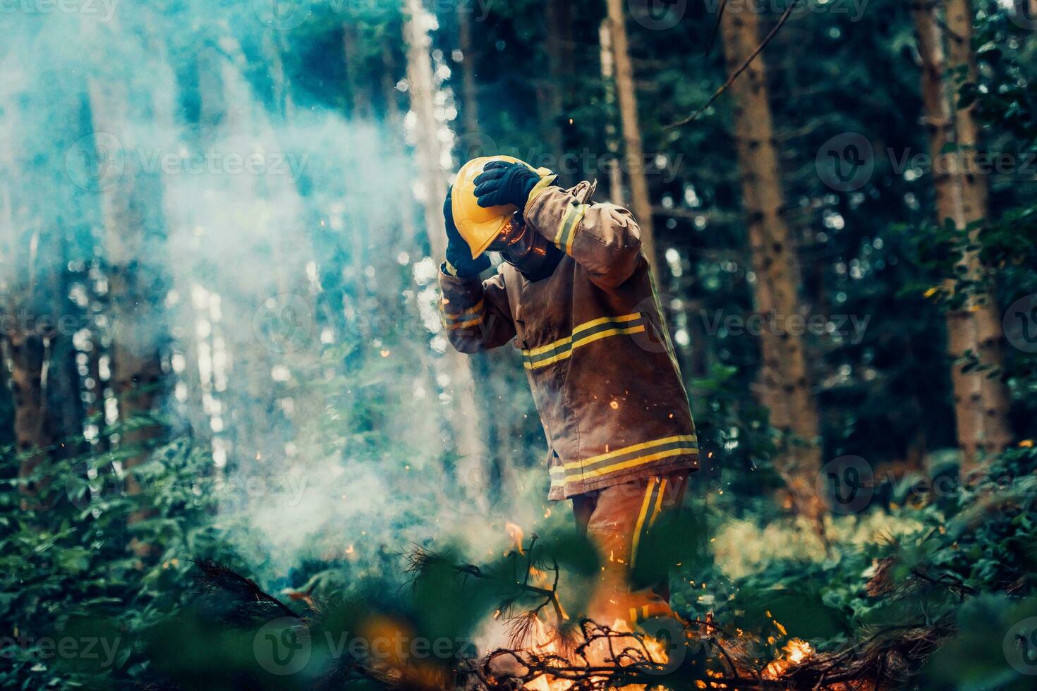 Firefighter at job. Firefighter in dangerous forest areas surrounded by strong fire. Concept of the work of the fire service photo