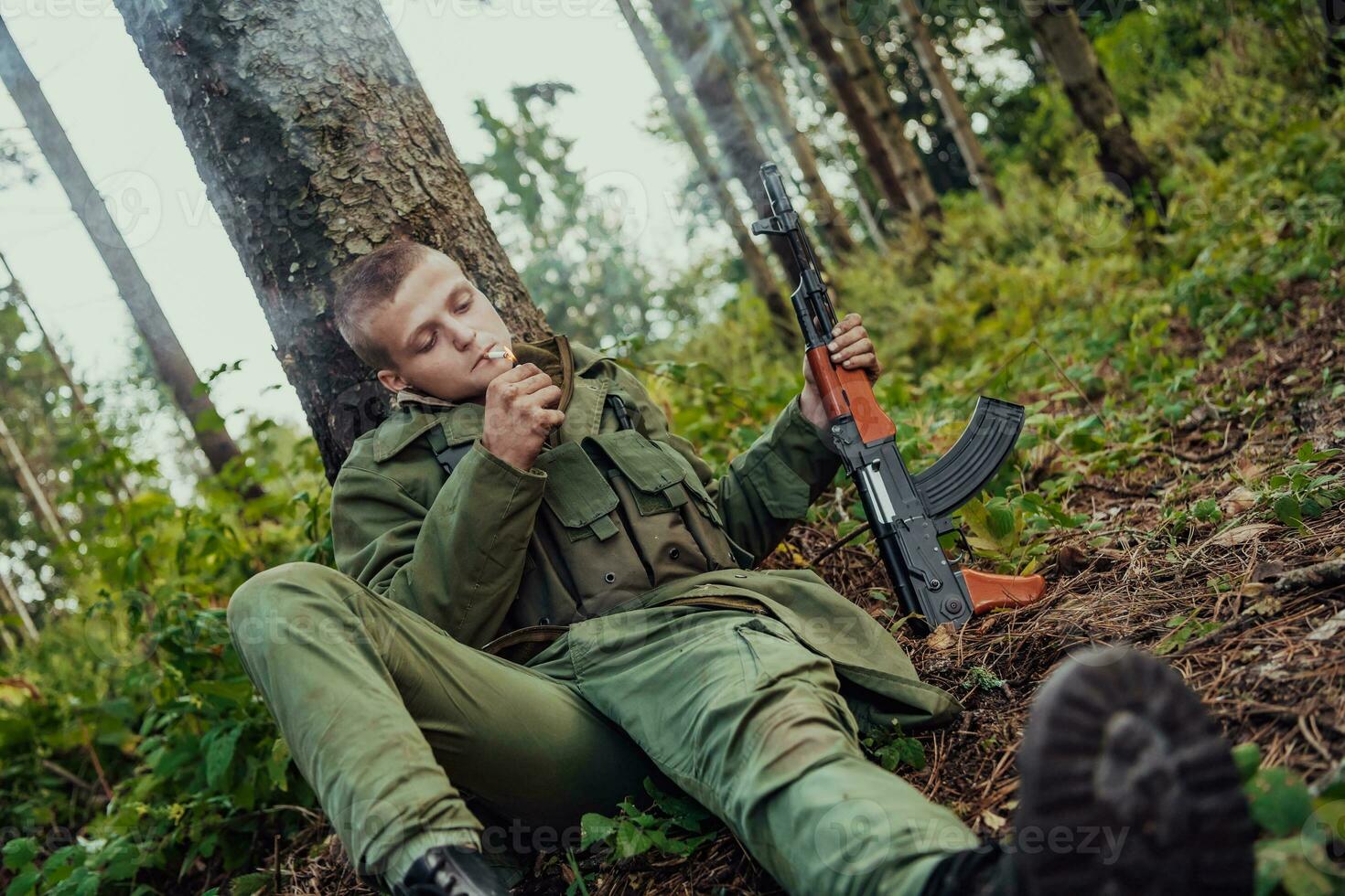 Terrorist have a break and smoke cigarette in forest during battle photo