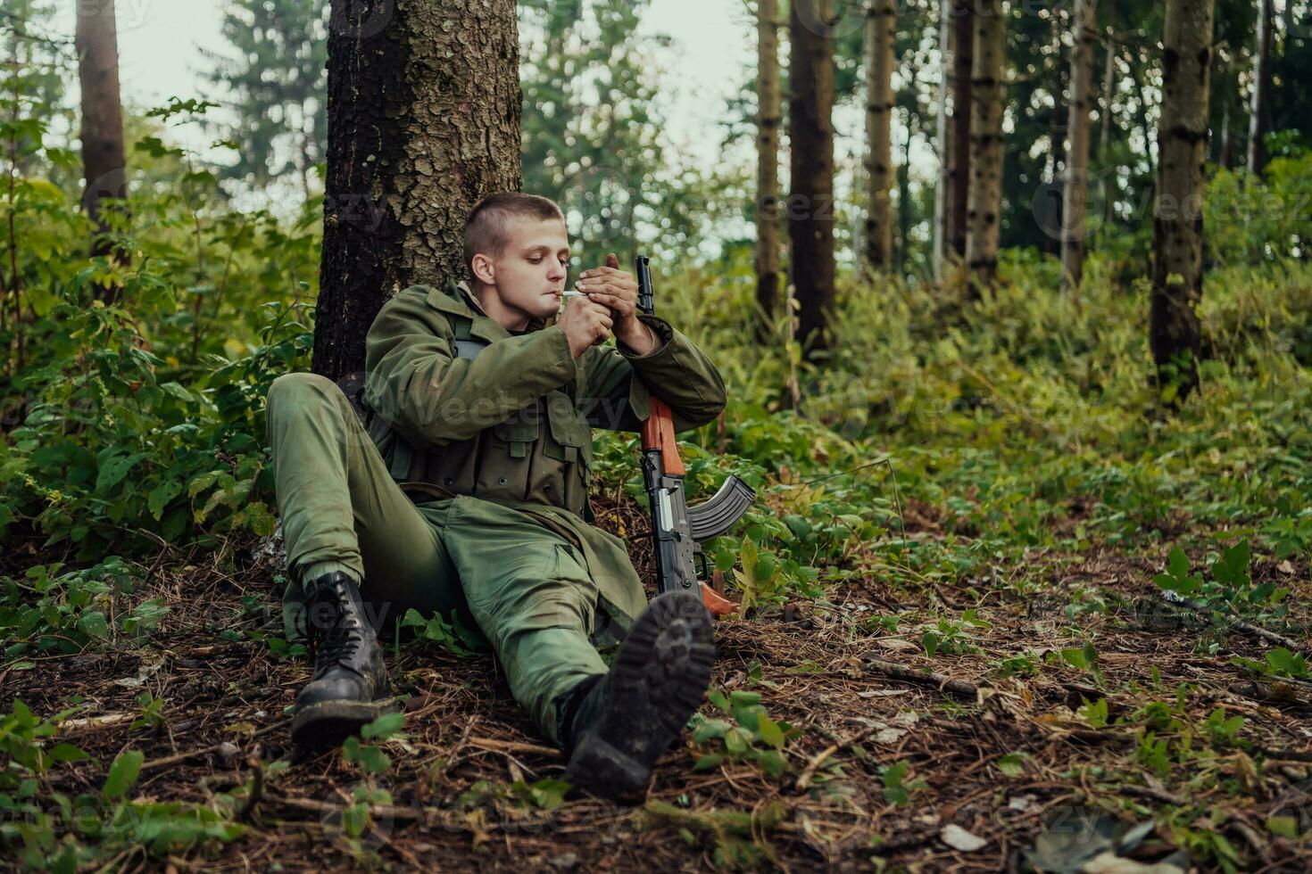 terrorista tener un descanso y fumar cigarrillo en bosque durante batalla foto