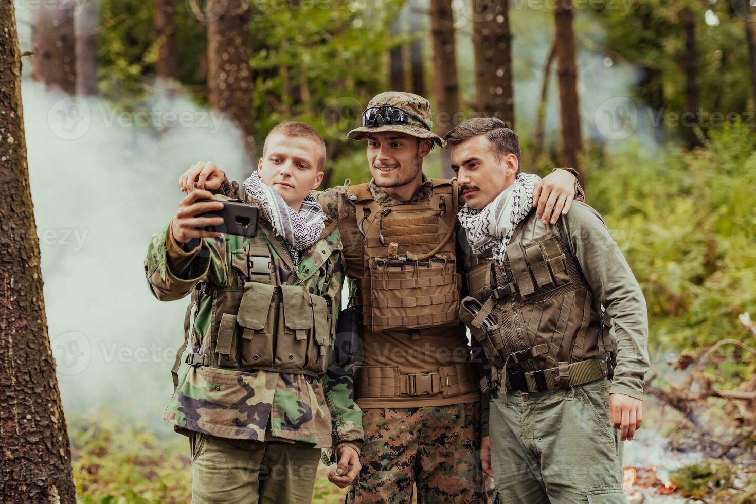 equipo de soldados y terrorista tomando selfie con teléfono inteligente en el bosque foto