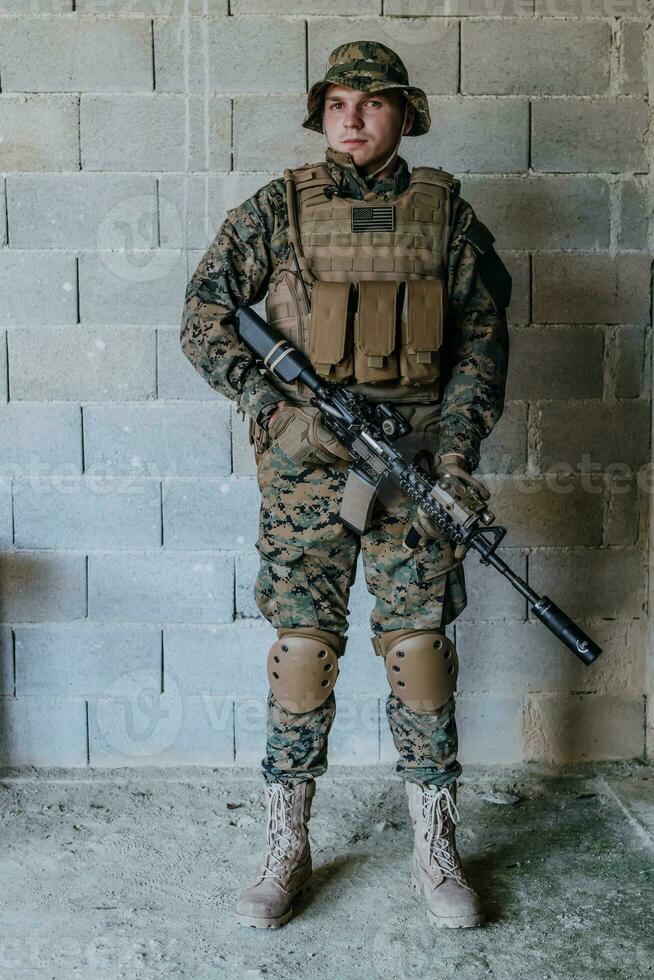 A soldier in uniform stands in front of a stone wall in full war gear preparing for battle photo