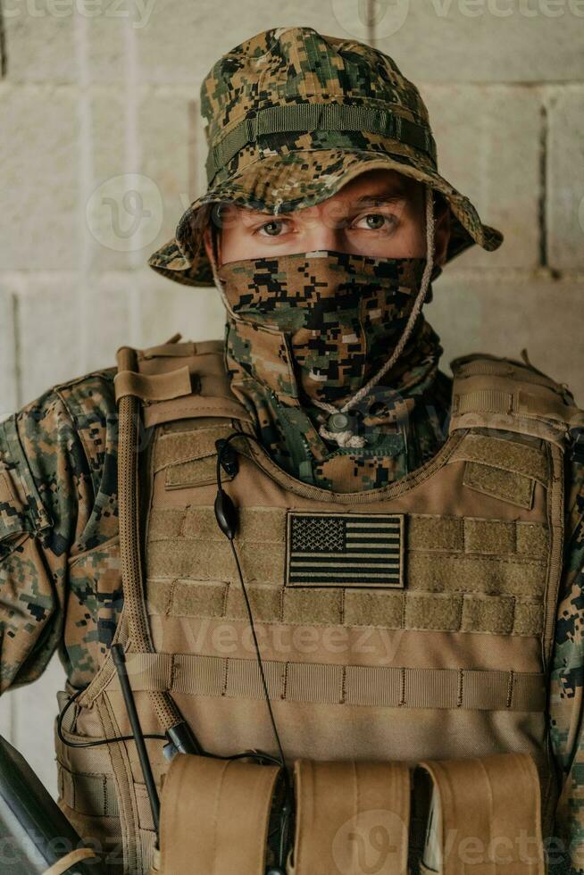 A soldier in uniform stands in front of a stone wall in full war gear preparing for battle photo