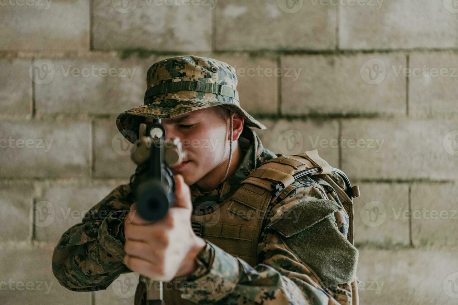 A soldier in uniform stands in front of a stone wall in full war gear preparing for battle photo