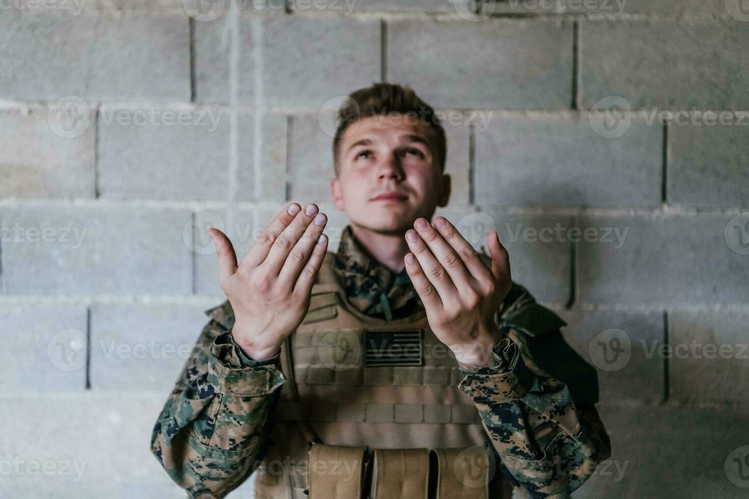 A Muslim soldier of the special forces prays to God by raising his hands and starts a prayer photo