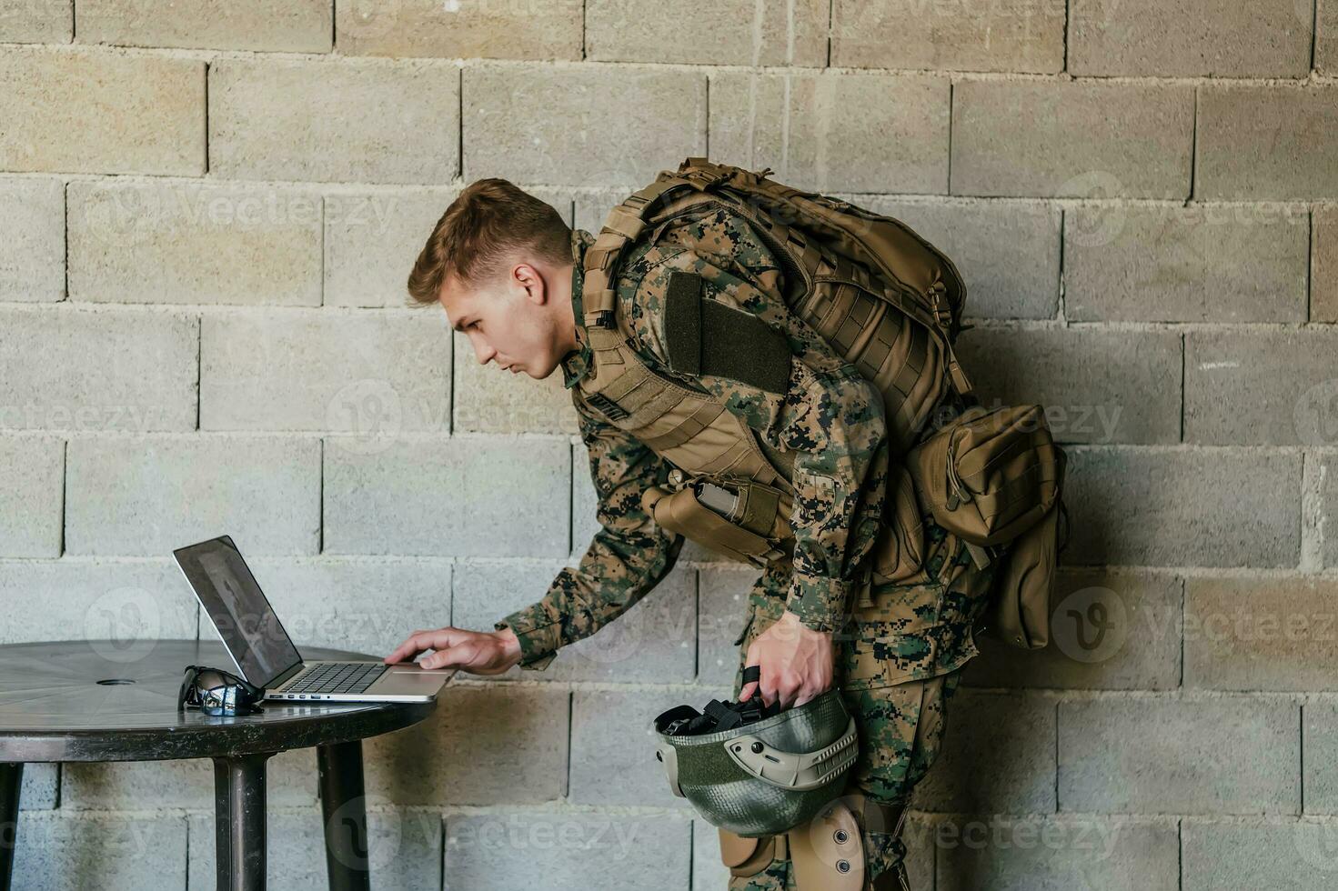 American soldier in military uniform using laptop computer for drone controlling and to stay in contact with friends and family photo