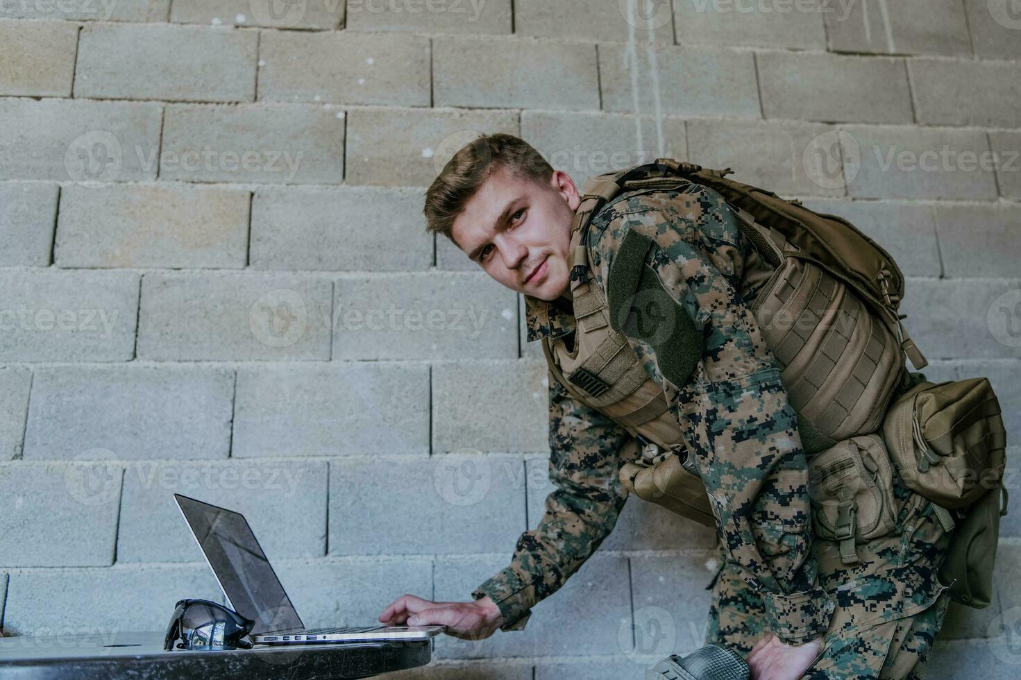 American soldier in military uniform using laptop computer for drone controlling and to stay in contact with friends and family photo