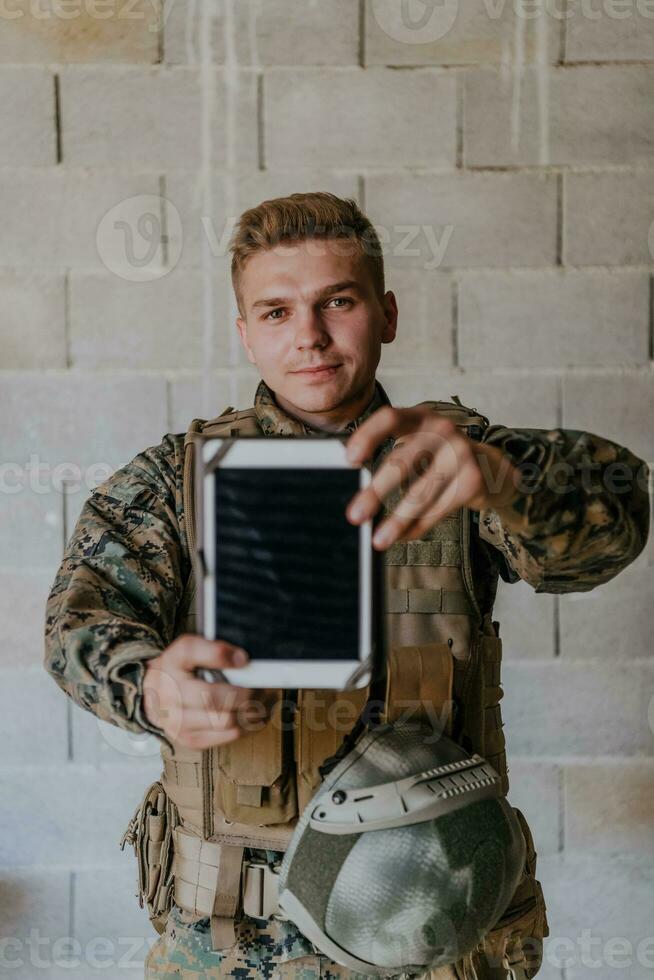 Soldier using tablet computer against old brick wall photo