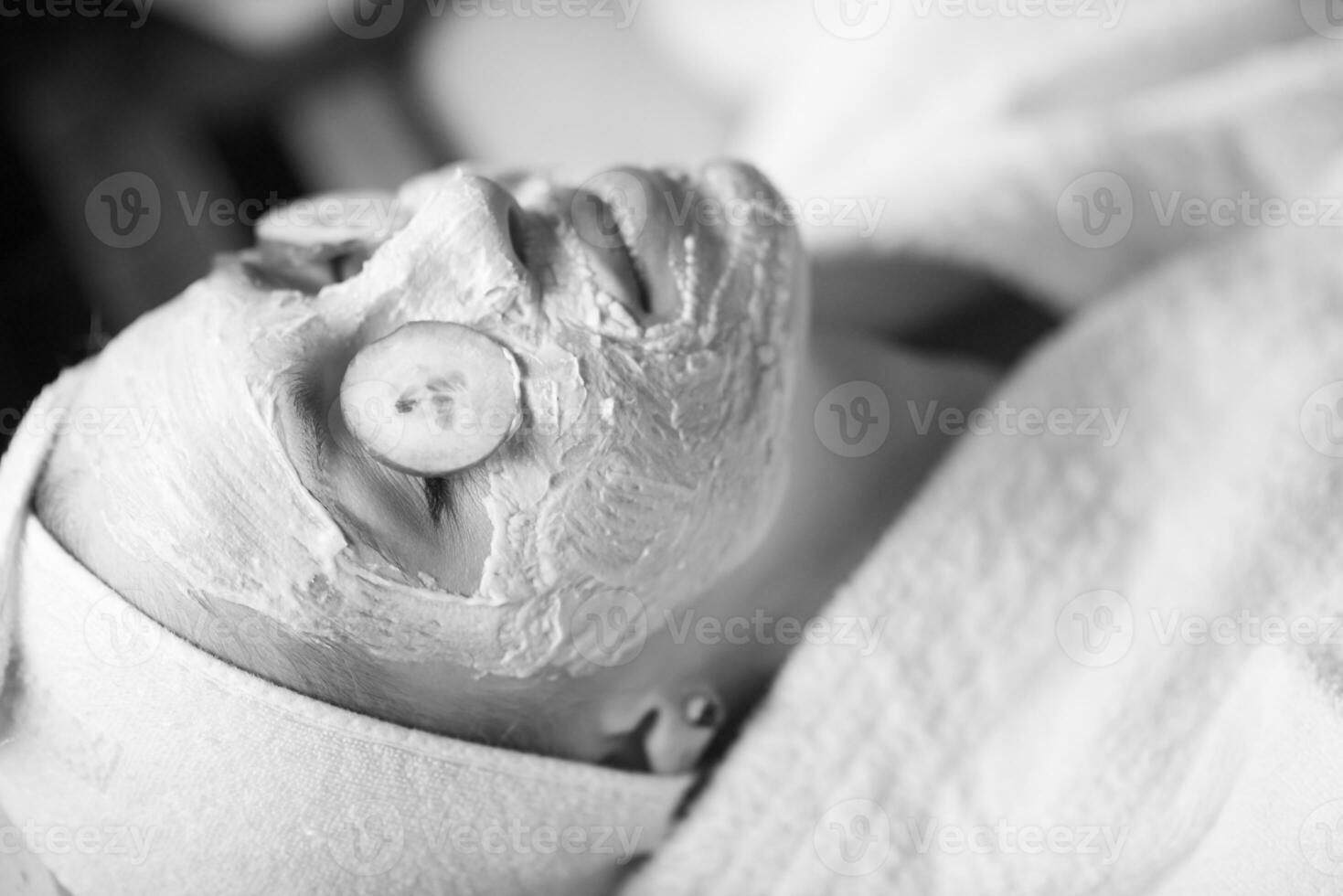 woman is getting facial clay mask at spa photo