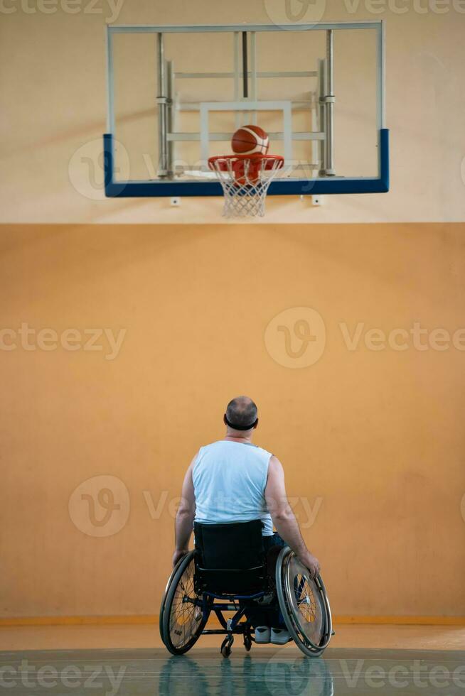 un inválido de guerra en silla de ruedas entrena con una pelota en un club de baloncesto en entrenamiento con equipo deportivo profesional para discapacitados. el concepto de deporte para personas con discapacidad foto