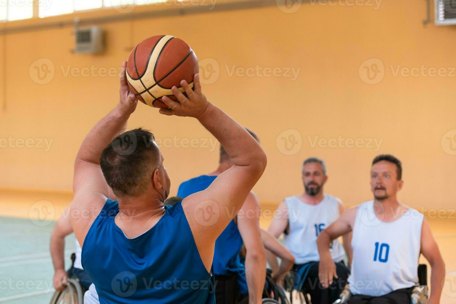 Disabled War veterans mixed race opposing basketball teams in wheelchairs photographed in action while playing an important match in a modern hall. photo