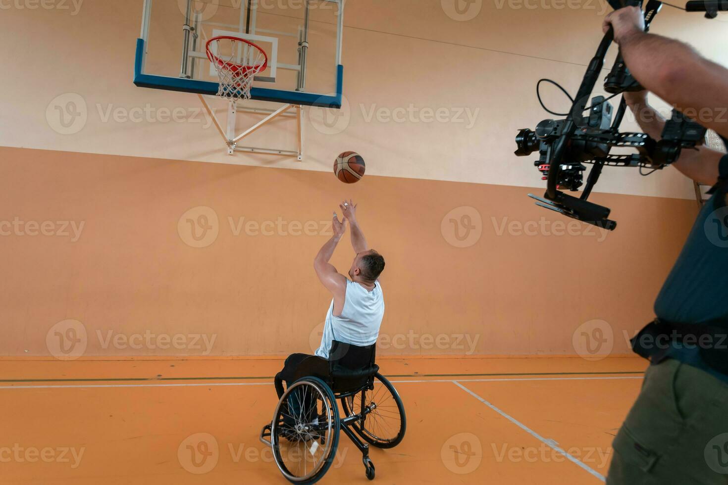 un camarógrafo con equipo profesional graba un partido de la selección nacional en silla de ruedas jugando un partido en la arena foto