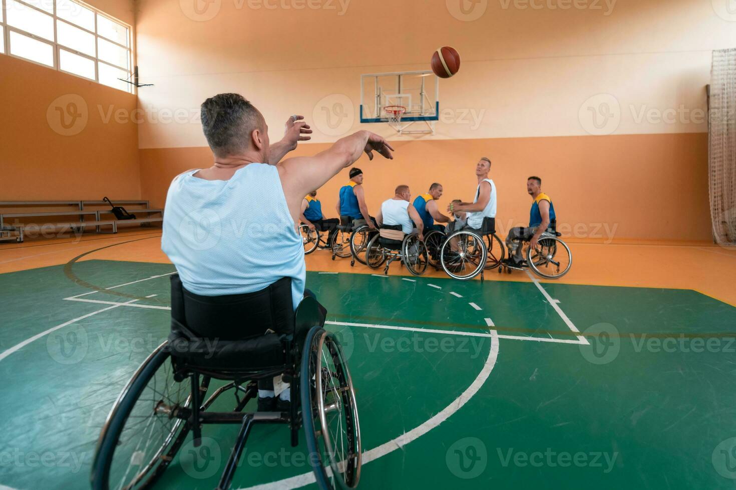 Disabled War veterans mixed race and age basketball teams in wheelchairs playing a training match in a sports gym hall. Handicapped people rehabilitation and inclusion concept photo