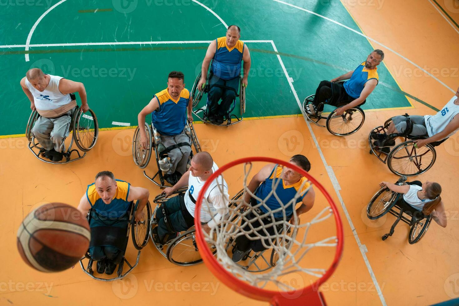 Disabled War or work veterans mixed race and age basketball teams in wheelchairs playing a training match in a sports gym hall. Handicapped people rehabilitation and inclusion concept. photo