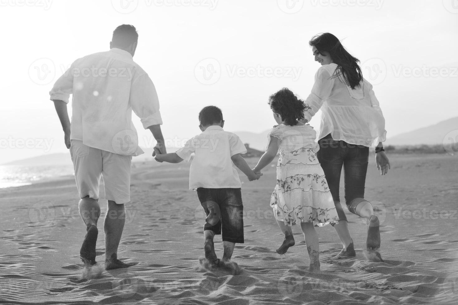 familia joven feliz divertirse en la playa al atardecer foto