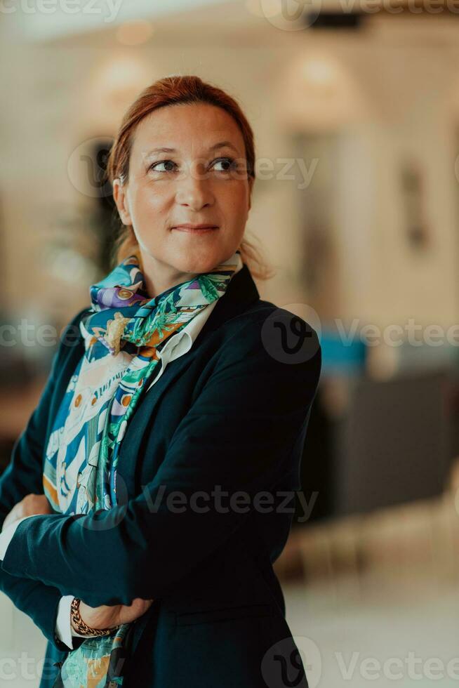 retrato de negocio mayor mujer con cruzado brazos en pie en moderno corporación. selectivo atención foto