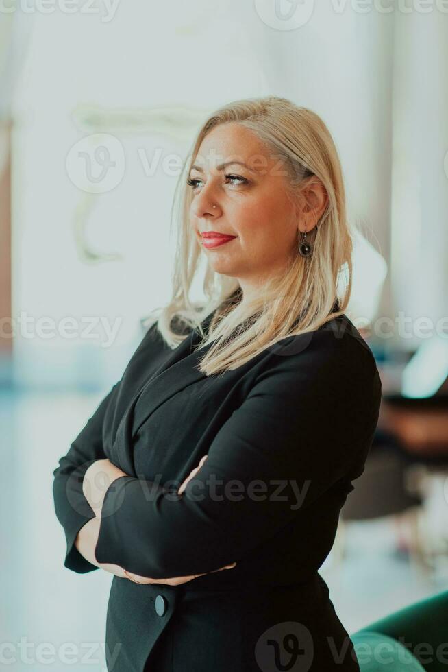 Portrait of business senior woman with crossed arms standing in modern corporation. Selective focus photo