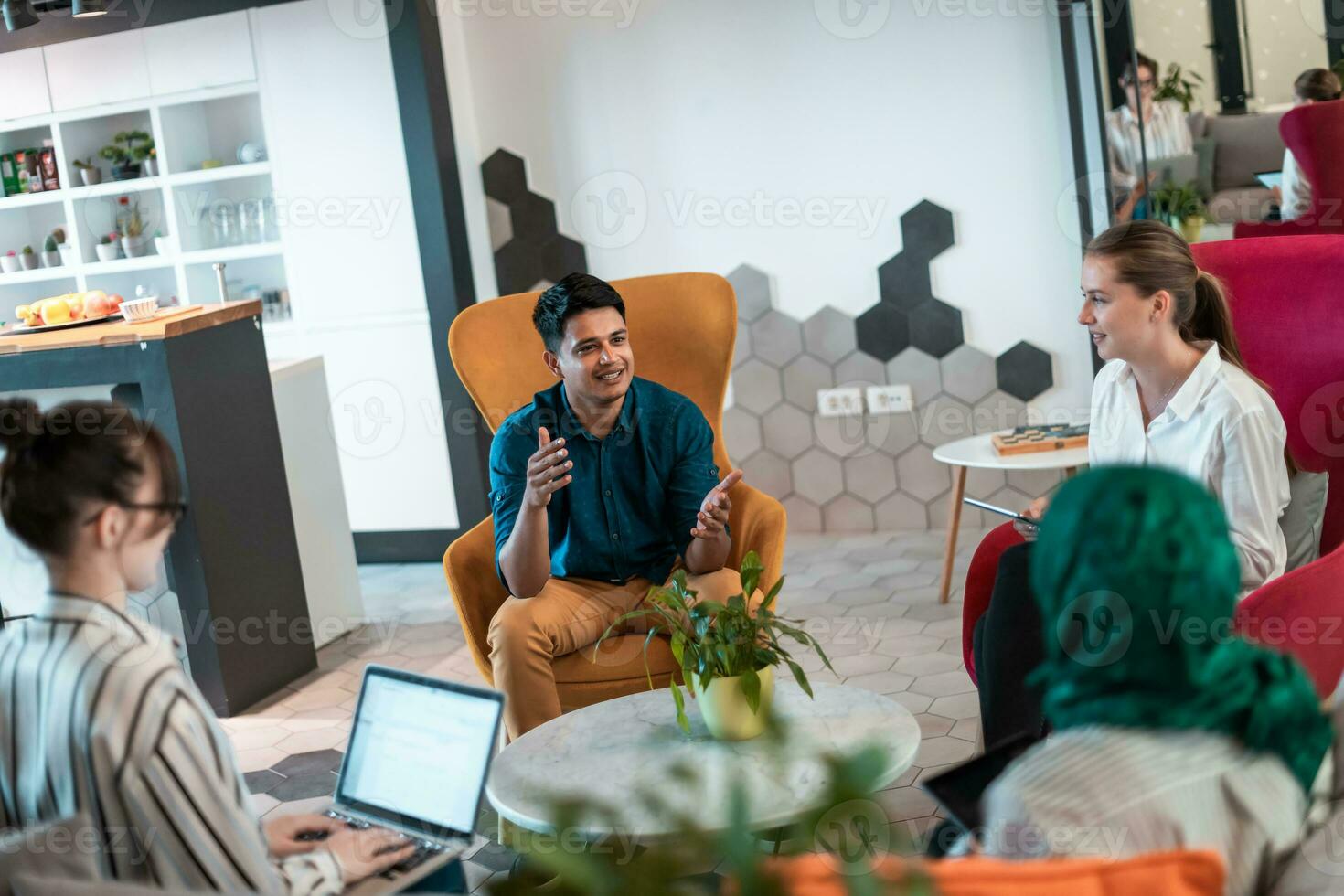 Multiethnic startup business team having brainstorming in relaxation area of modern office interior working on laptop and tablet computer photo