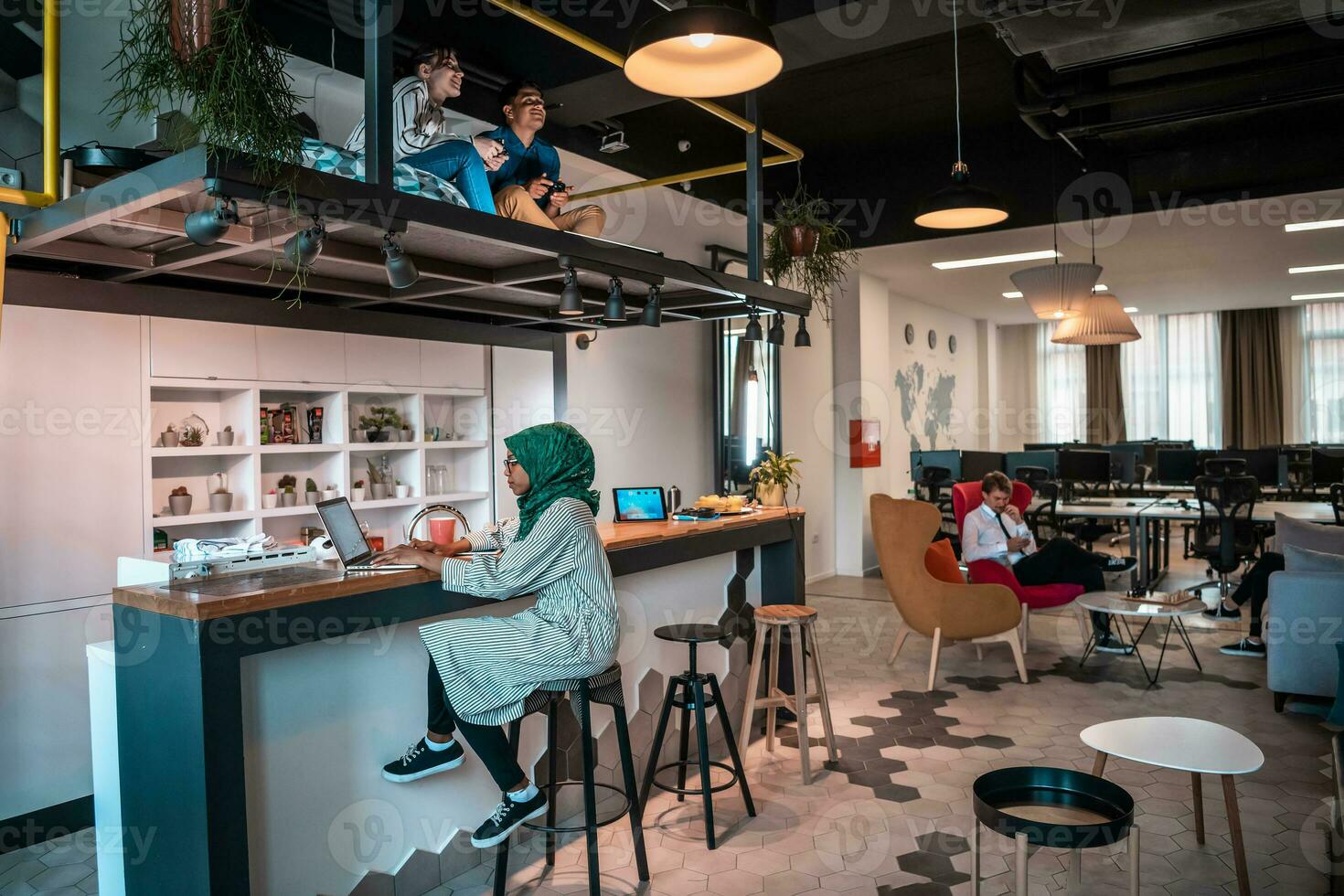 Group of casual multiethnic business people taking break from the work doing different things while enjoying free time in relaxation area at modern open plan startup office photo